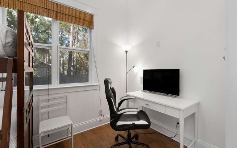 Your bright workspace features a sleek desk, comfortable chair, and TV - perfect for remote work with peaceful garden views.
