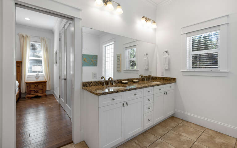 Refresh in your spacious bathroom featuring dual sinks, granite counters, and bright natural light from large windows.