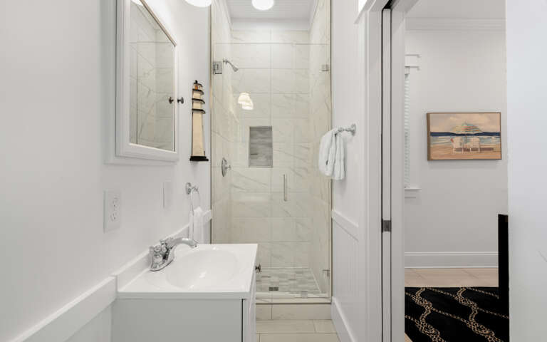 Step into your pristine bathroom with marble shower, fresh towels, and coastal artwork creating a spa-like retreat.