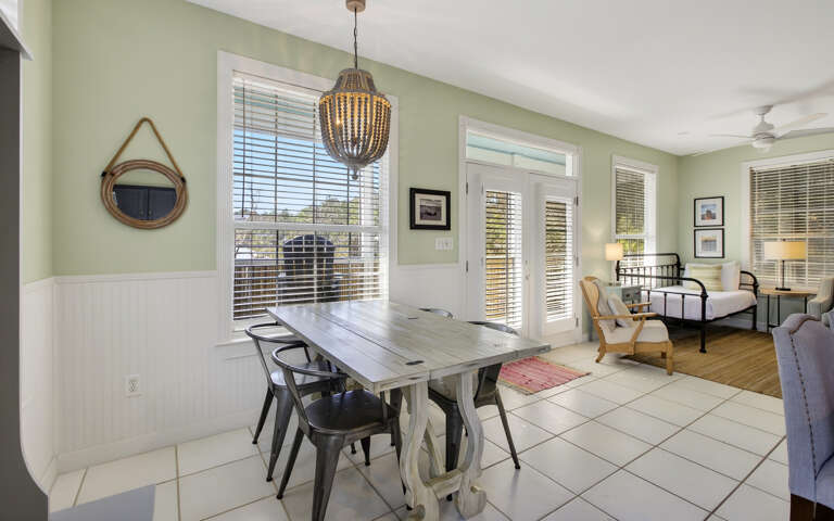 Gather around this rustic dining table where memories are made, with natural light streaming through French doors.