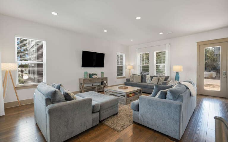 Sink into plush blue seating while natural light streams through bright windows, creating your perfect retreat for movie nights.