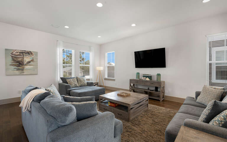 Sink into plush sofas while watching your favorite shows on the wall-mounted TV in this bright, coastal-inspired living space.