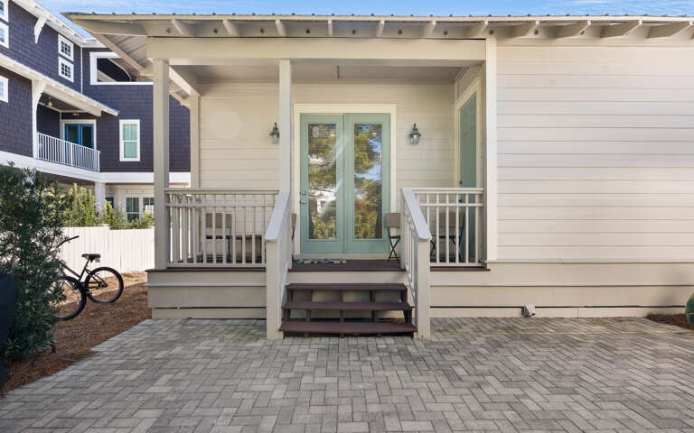 Charming coastal home entrance with covered porch and peaceful neighborhood setting for your beach getaway.