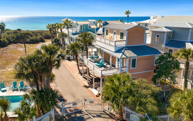 Stunning gulf front community featuring colorful coastal homes with palm trees and pristine turquoise waters just steps away.