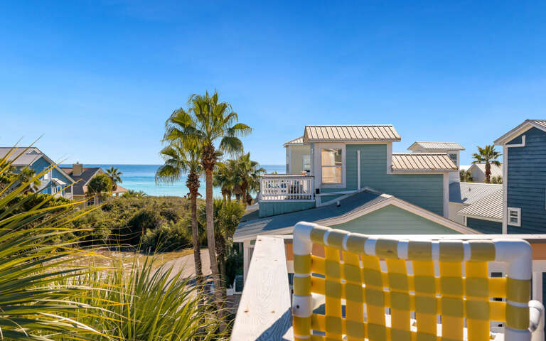 Coastal community setting with beach houses and palm trees near turquoise waters.