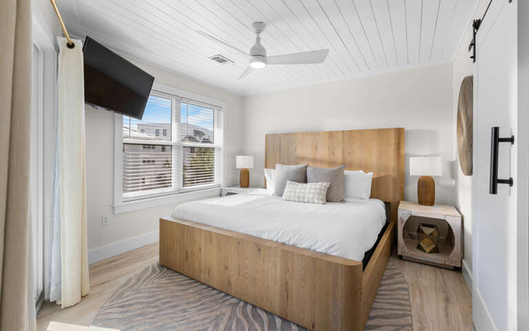 Rest easy in your modern bedroom featuring a beautiful wood bed, cozy linens, and ceiling fan for your comfort.