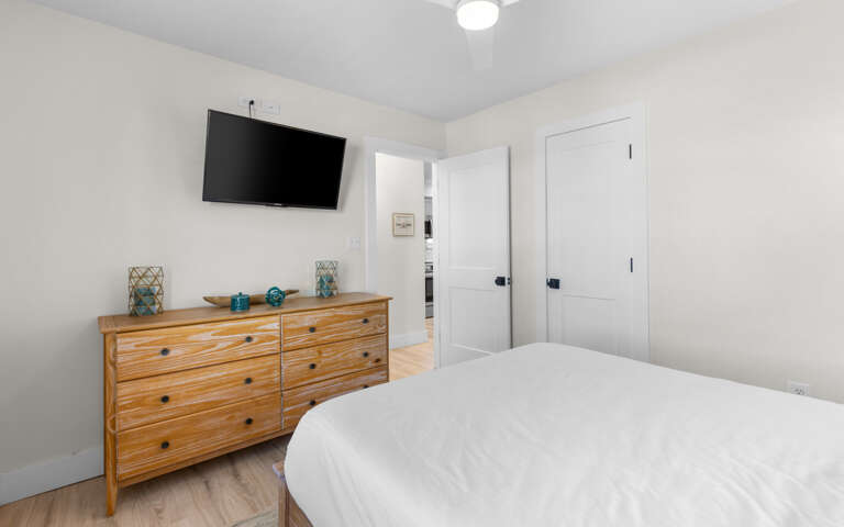 Sink into crisp linens in your bright, modern bedroom featuring sleek TV entertainment and stylish mid-century furnishings.