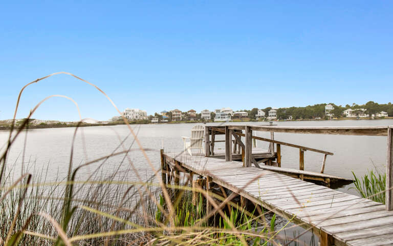 Wooden Pier Over Water With Residential Background