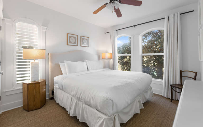 You'll love waking up in this serene bedroom with crisp white linens and warm natural light flooding through beautiful arched windows.