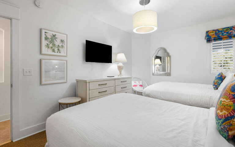 Sink into crisp white linens in your bright, tropical-themed bedroom with modern TV and thoughtful coastal touches for restful nights.
