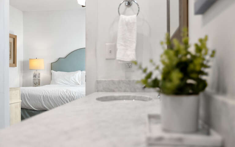 Unwind in your serene bedroom sanctuary where marble textures meet soft linens and fresh greenery creates a peaceful retreat.