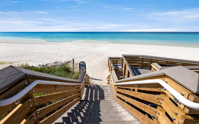 Wooden boardwalk provides direct beach access to pristine white sand and crystal-clear turquoise waters.