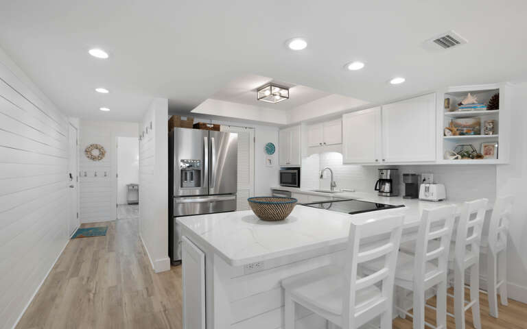 Your bright, modern kitchen awaits with sleek white cabinetry, stainless steel appliances, and a spacious island perfect for morning coffee or evening meals.