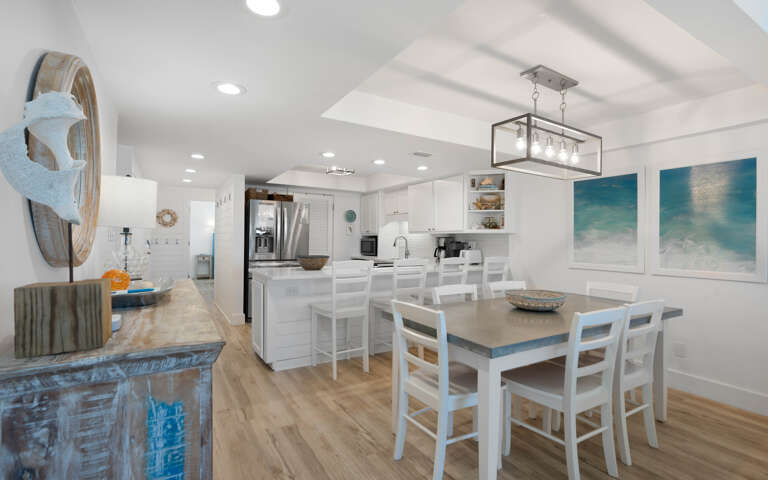 Your open-concept kitchen flows seamlessly into the dining area, where ocean-inspired artwork sets a calming coastal mood.