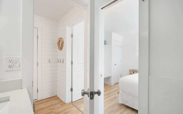 Step into your bright, airy retreat where crisp white walls and warm hardwood floors create a serene sanctuary for your coastal getaway.