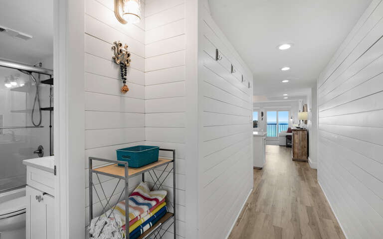 Walk through your bright hallway past the organized bathroom and into your coastal living space with gulf views beyond.