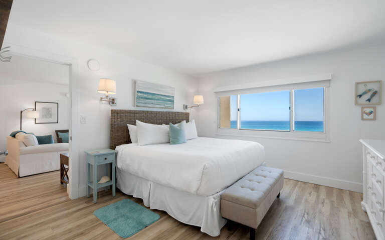 Wake up to stunning ocean views through your bedroom window, where crisp white linens and coastal decor create the perfect seaside retreat.