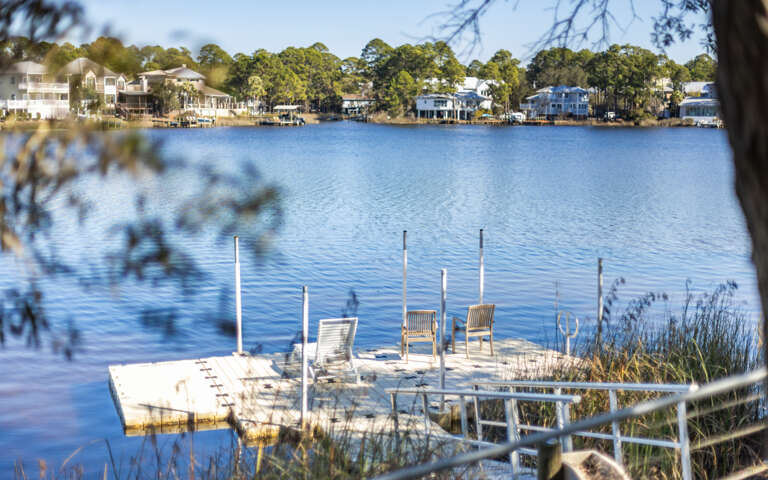 Peaceful lakefront setting with waterfront homes dotting the tree-lined shore across calm blue waters.