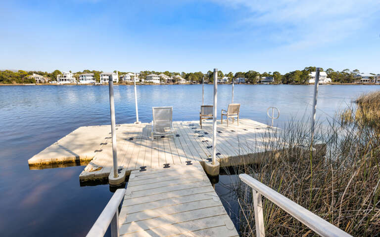 Private waterfront dock with comfortable seating overlooking serene lake and charming residential shoreline.