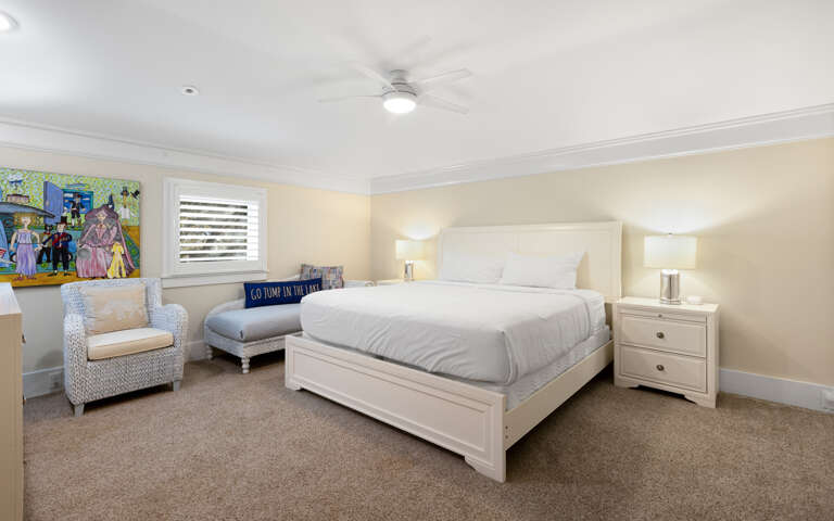 Sink into your cozy bedroom's plush white bedding and enjoy the ceiling fan's gentle breeze after exploring the colorful local art adorning the walls.