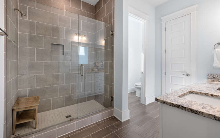 Step into your spa-like sanctuary with a gorgeous walk-in shower featuring elegant gray tiles and warm lighting for ultimate relaxation.