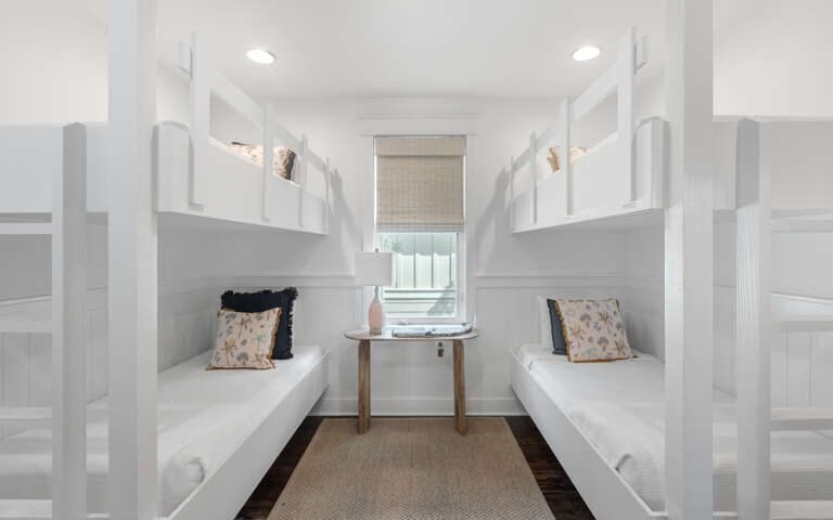 Room With Multiple Bunk Beds And A Desk Near A Window