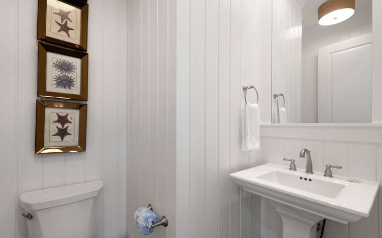 Step into your private coastal-themed bathroom with charming beadboard walls and nautical artwork that captures seaside serenity.