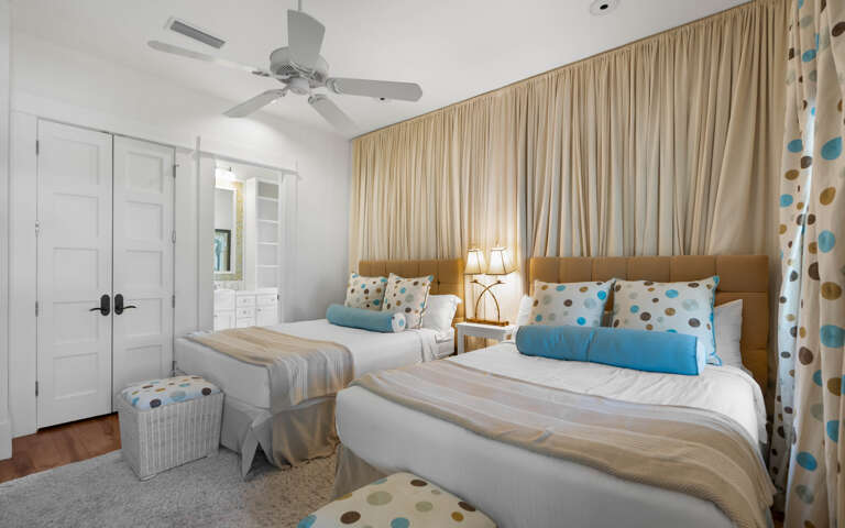 Unwind in your cheerful twin bedroom with playful polka dot accents, plush bedding, and a gentle ceiling fan for perfect comfort.