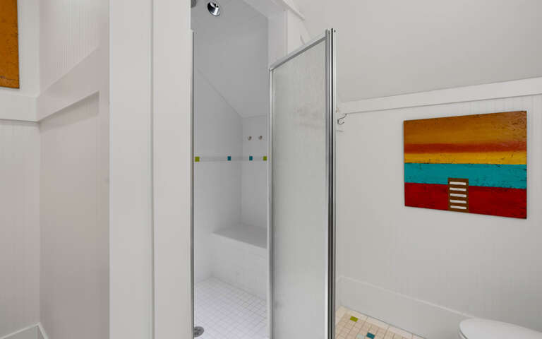Step into your bright, modern bathroom featuring a spacious glass-enclosed shower and vibrant artwork that adds personality to your morning routine.