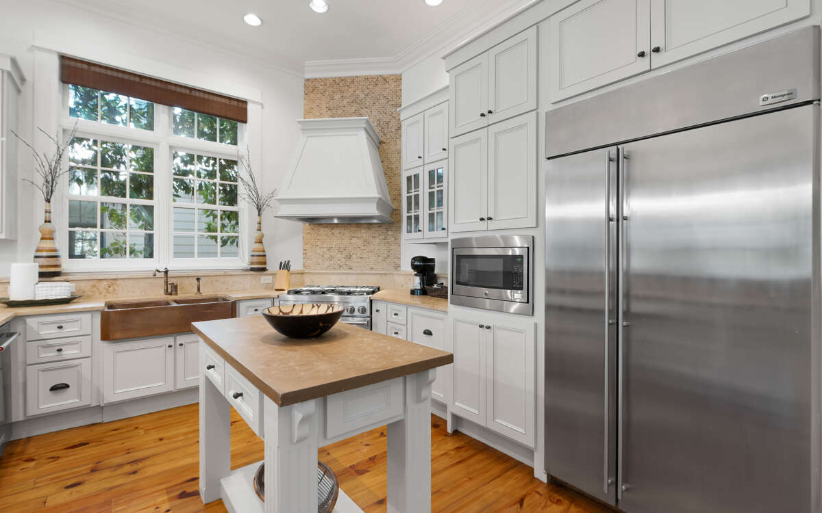 Your gourmet kitchen awaits with professional-grade appliances, butcher block island, and abundant natural light filtering through garden windows.