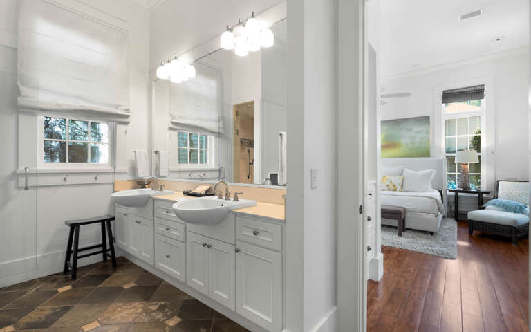 Pamper yourself in this elegantly appointed bathroom with dual vanities, modern lighting, and peaceful bedroom views.