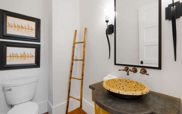 Step into your stylishly designed powder room featuring a striking woven vessel sink and warm brass fixtures that create an inviting, spa-like atmosphere.