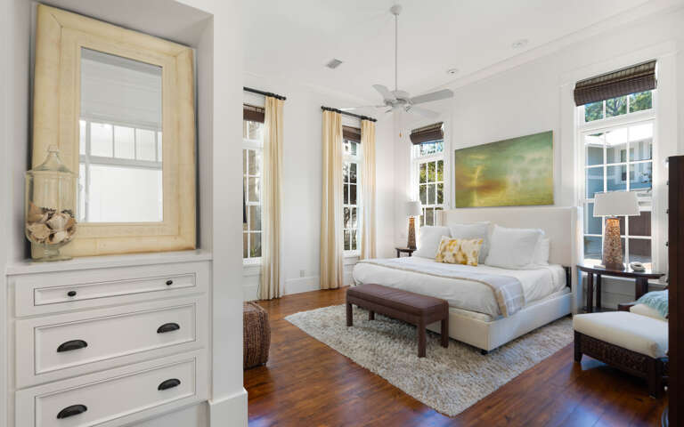 Unwind in your serene bedroom sanctuary with crisp white linens, warm wood floors, and natural light streaming through elegant windows.