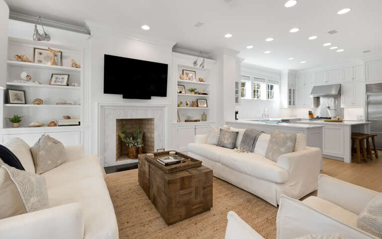 Sink into plush white sofas by the fireplace while your favorite shows play on the wall-mounted TV in this bright, open living space.