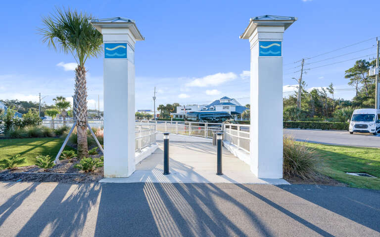 Property entrance with white columns and blue wave logos leading to marina area.