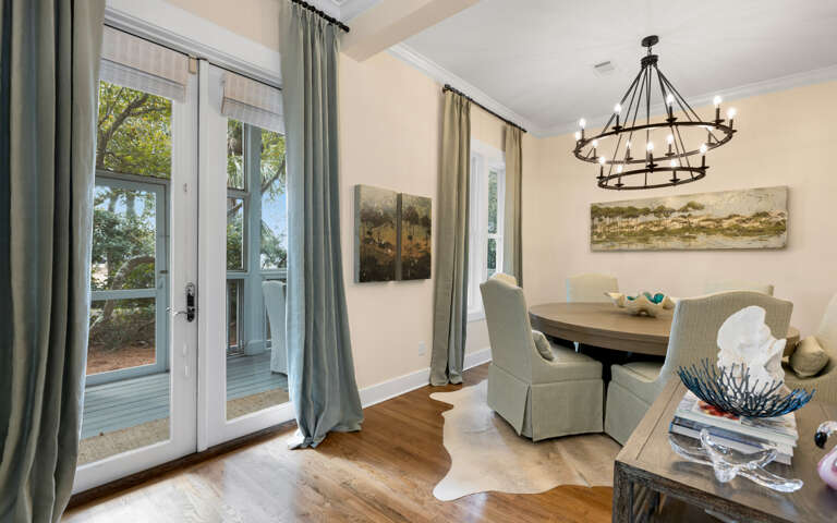 Gather around your elegant dining table where warm light from the wrought-iron chandelier creates the perfect atmosphere for memorable meals together.