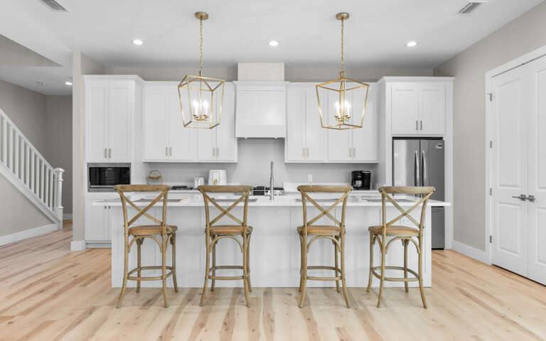 Your bright kitchen awaits with gleaming white cabinets, marble countertops, and cozy breakfast bar seating for four.