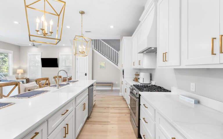 Your gourmet kitchen awaits with sleek white cabinets, gleaming countertops, and stylish brass fixtures that catch the light beautifully.