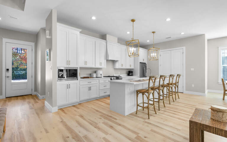 You'll love cooking in this bright, modern kitchen featuring pristine white cabinets, elegant brass pendant lights, and a spacious island perfect for gathering.