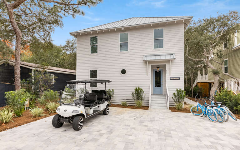Two-story White House With Golf Cart And Bicycles Parked In Front Two-story White House With Golf Cart And Bicycles Parked In Front