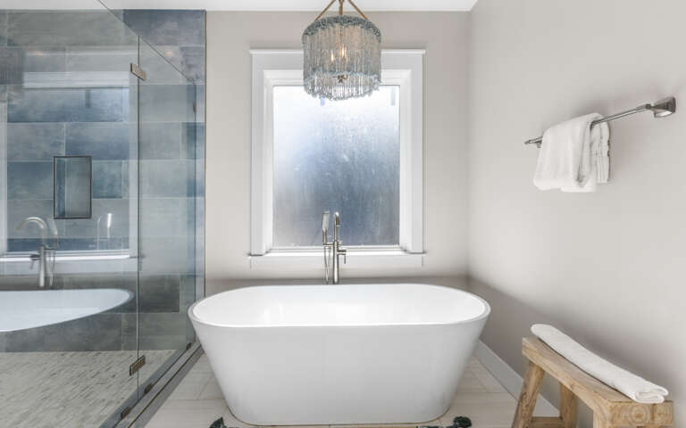 Indulge in your private spa retreat with a luxurious soaking tub, rainfall shower, and elegant chandelier creating the perfect ambiance for relaxation.