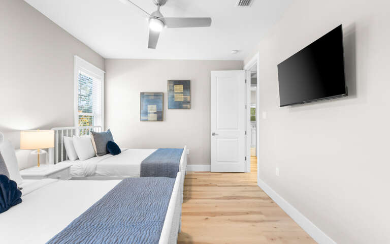 Unwind in your bright bedroom with two comfortable beds, modern TV, and gentle ceiling fan for perfect temperature control.