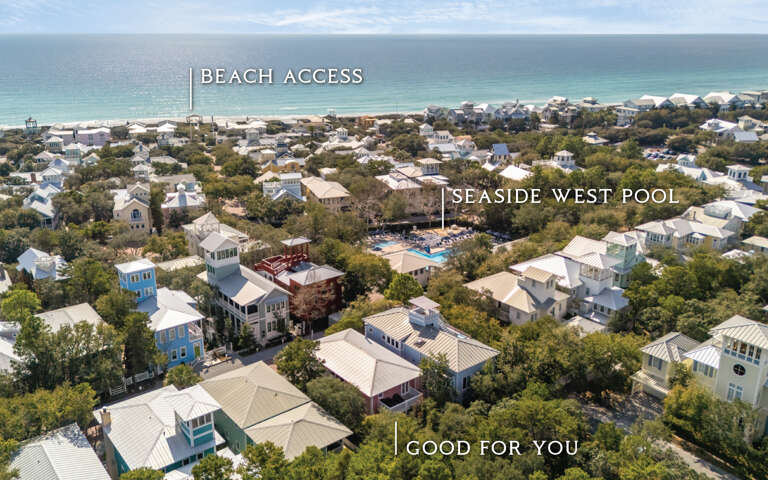 Aerial view of a charming beachside community with tree-lined streets leading to pristine white sand beaches and turquoise waters.