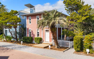 Charming coastal cottages nestled among palm trees and lush landscaping create a welcoming seaside retreat atmosphere.