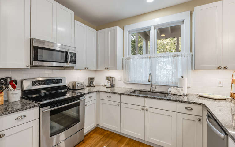 Your fully equipped kitchen awaits with granite counters, stainless appliances, and charming garden views through the window.