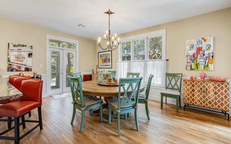 Gather around your beautiful dining table with vibrant green chairs and warm wood floors creating the perfect space for memorable meals together.