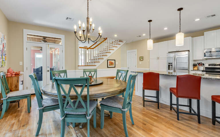 Gather around the welcoming dining table where your morning coffee meets evening conversations, flowing seamlessly into a bright kitchen perfect for cooking.