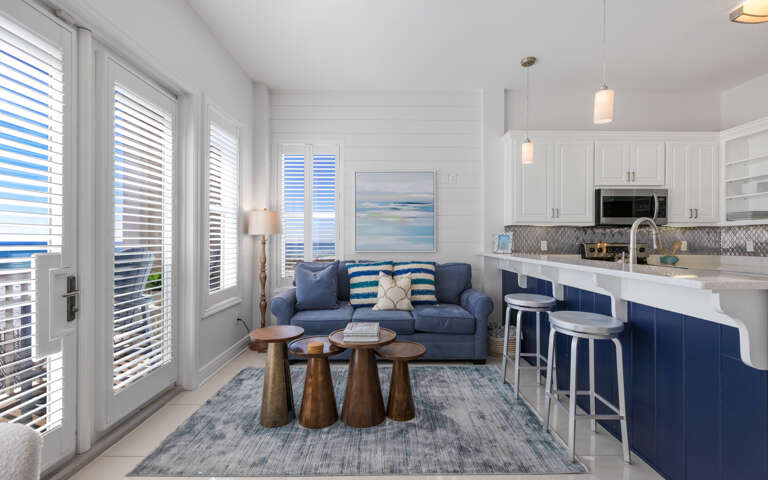 Your bright coastal retreat features an open-concept living space where blue accents meet crisp whites, creating the perfect backdrop for your beach getaway.