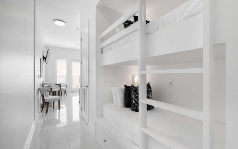 Your modern white bunk bed sanctuary offers space-saving comfort with built-in storage and individual reading lights for peaceful nights.