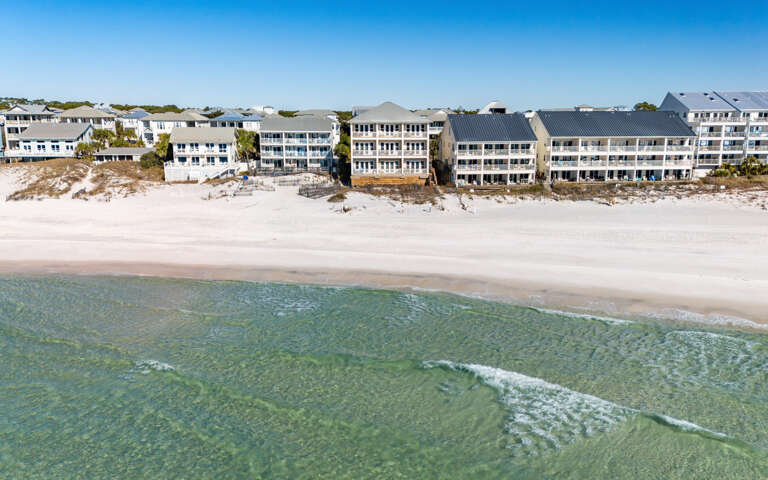 Gulf front property complex with direct access to pristine white sand and crystal-clear emerald waters.